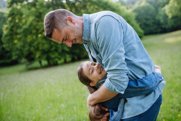 Father with daughter, playing at meadow, hugging, having fun. Concept of fathers's Day and fatherly love.