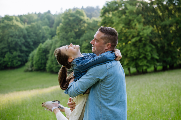 Father with daughter, playing at meadow, hugging, having fun. Concept of fathers's Day and fatherly love.