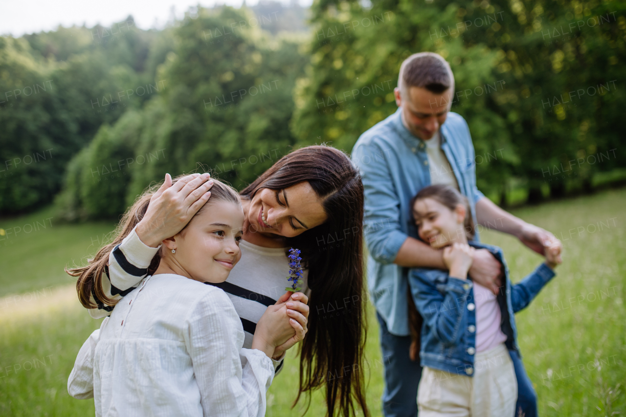 Beautfiul young family at meadow, enjoying together time, laughing, having fun.