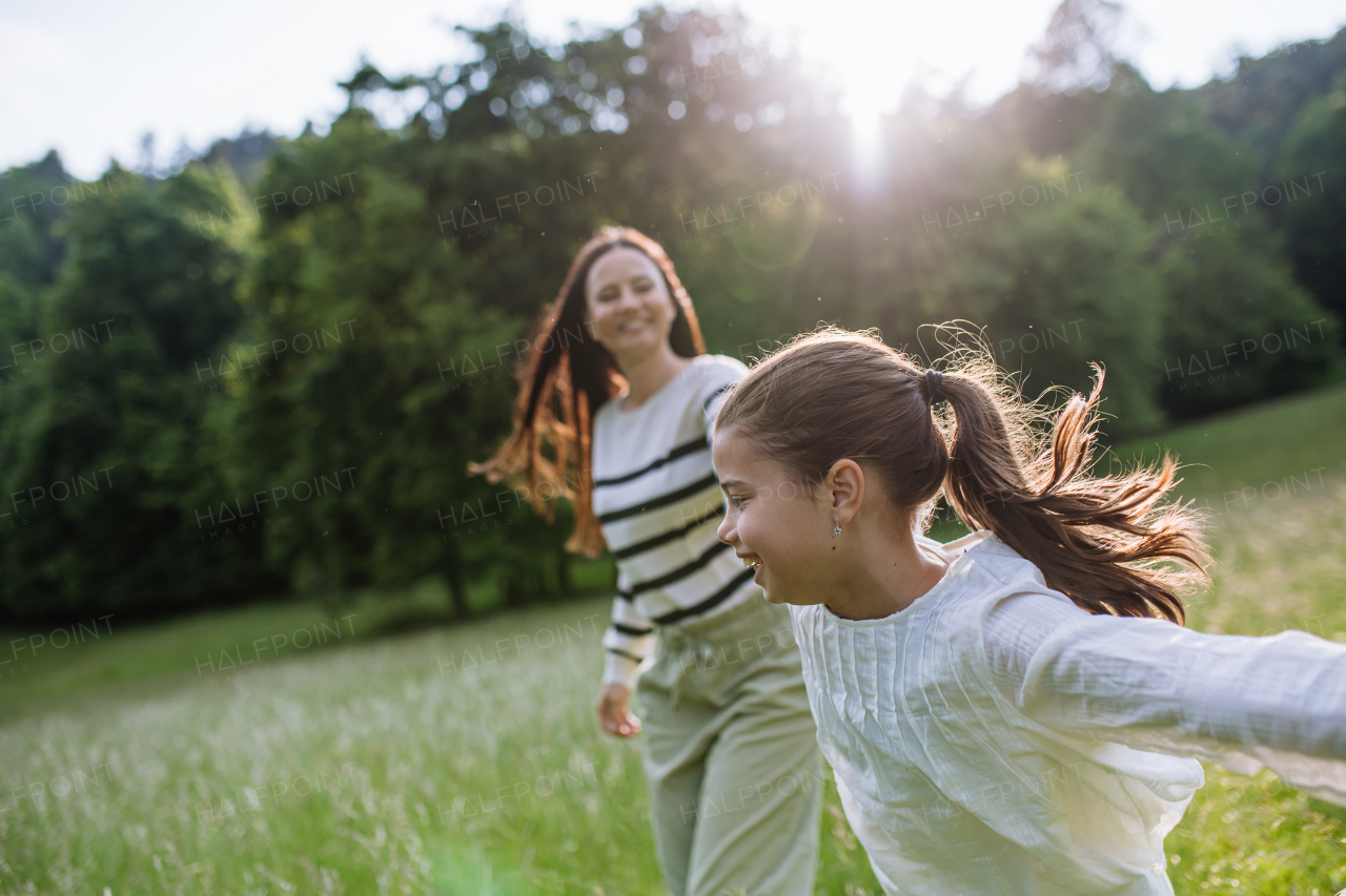 Beautiful mother with daughter, playing at meadow, running and having fun. Concept of Mother's Day and maternal love.