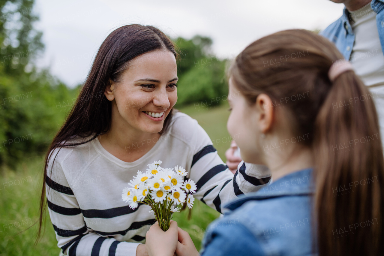 Daughter picking flowers, giving them to mother. Concept of family ecological hobby in nature and Mother's Day.