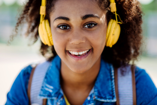 Multiracial girl enjoying music in headphones, outdoor in a city.