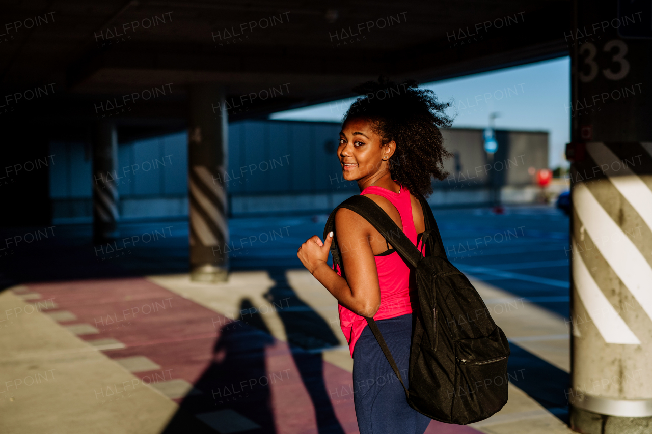 Multiracial teenage girl walking with a backpack in modern city during summer day, back to school concept.