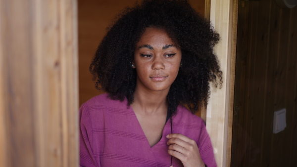 A peaceful morning for young woman standing on balcony in bathrobe, looking at beautiful nature around her, smiling.