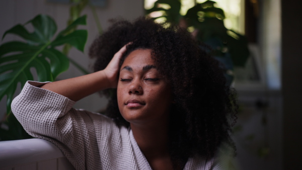 A pensive woman sitting by bathtub, lush indoor plants around her. Woman getting ready for bath, enjoying peaceful morning moment alone