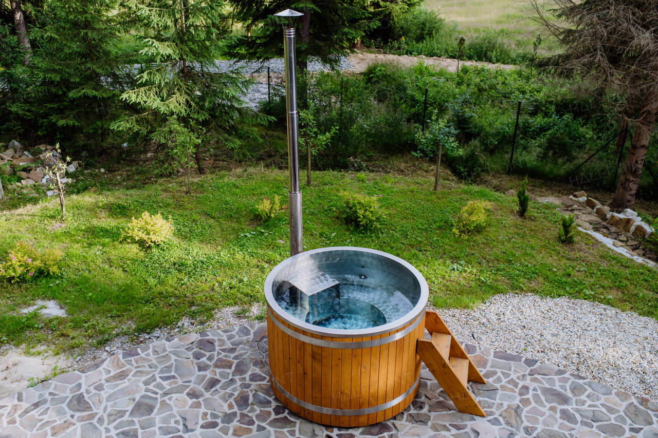 A wooden bathtub with a fireplace to burn wood and heat water in backyard in mountains.