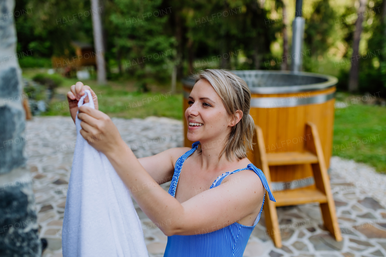 A young woman preapring to get into hot bath outdoors. Summer holidays in the mountains, hot water treatments and thermal spa concept.