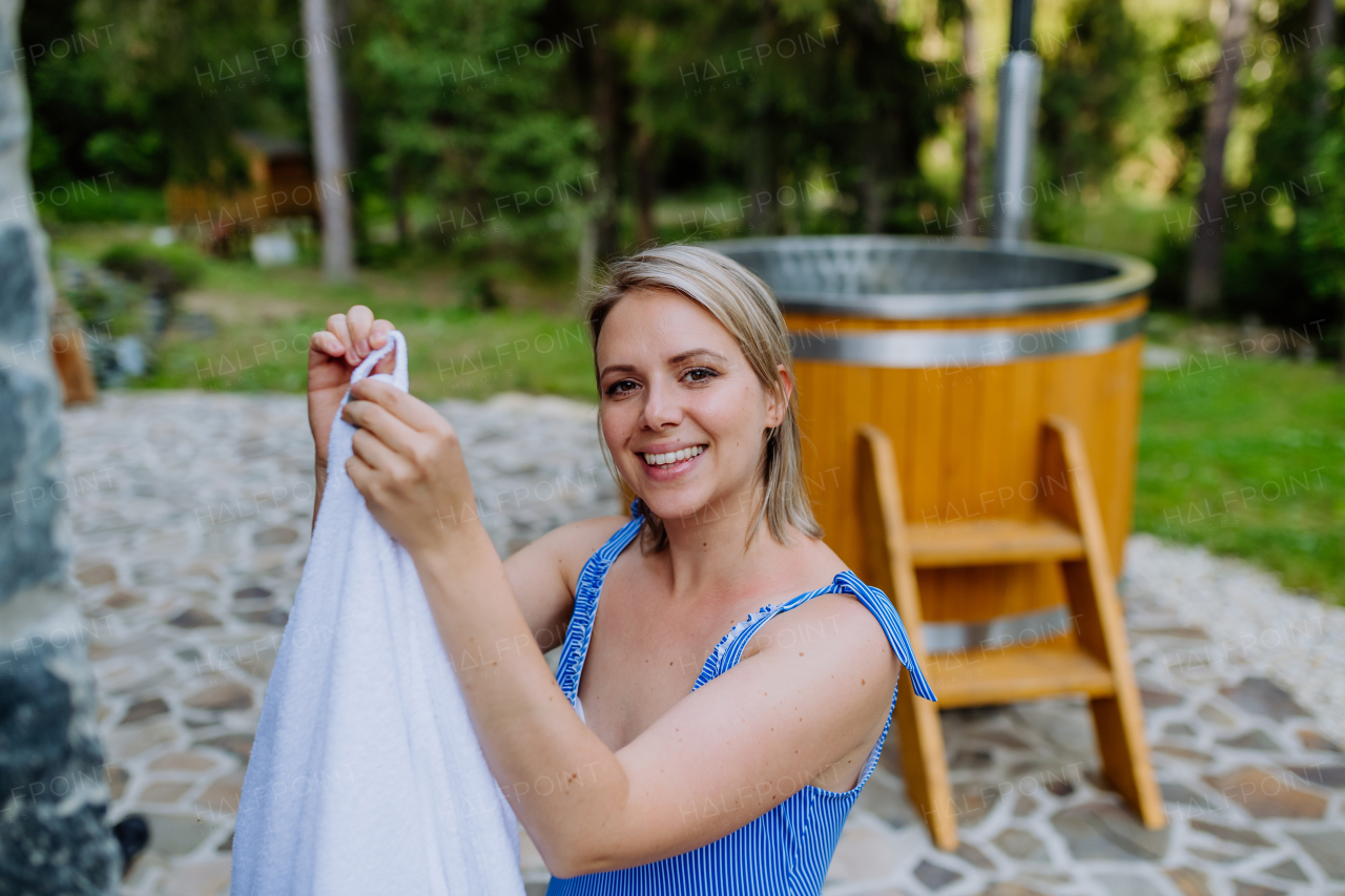 A young woman preapring to get into hot bath outdoors. Summer holidays in the mountains, hot water treatments and thermal spa concept.