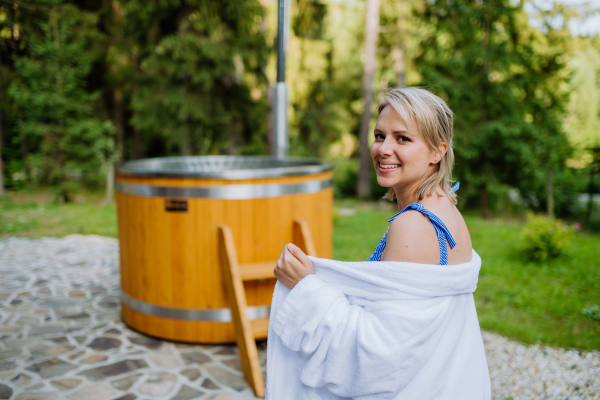 A young woman preapring to get into hot bath outdoors. Summer holidays in the mountains, hot water treatments and thermal spa concept.