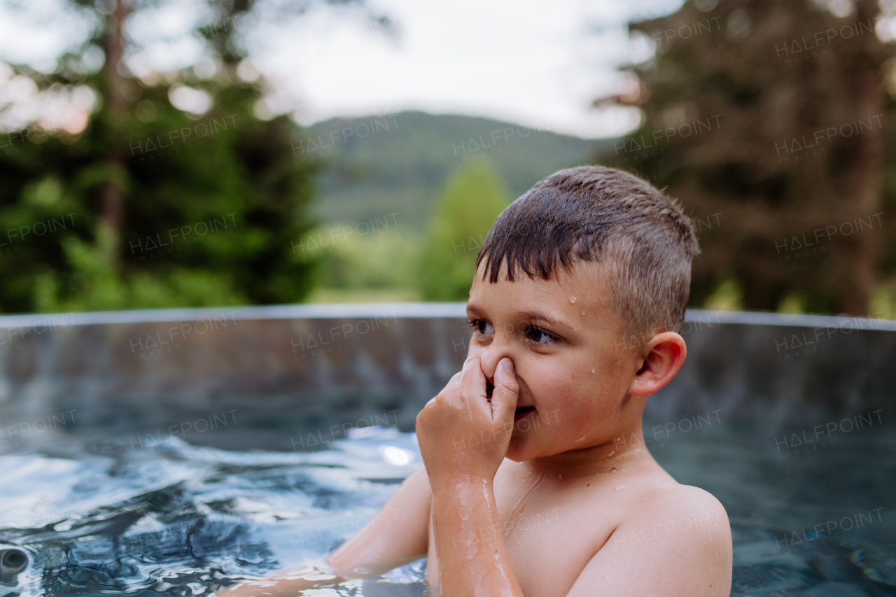 High angle view of little boy having fun in hot tub, trying to dive. Summer holiday, vacation concept.