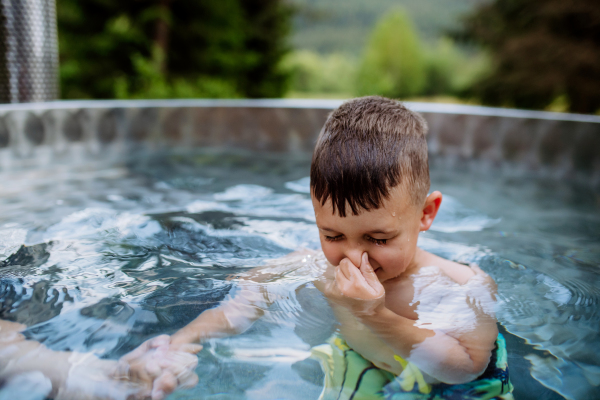 High angle view of little boy relaxing with eyes closed in hot tub, trying to dive. Summer holiday, vacation concept.