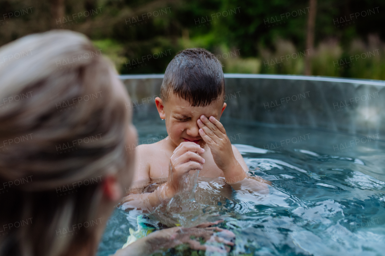 High angle view of little boy having fun in hot tub, trying to dive. Summer holiday, vacation concept.