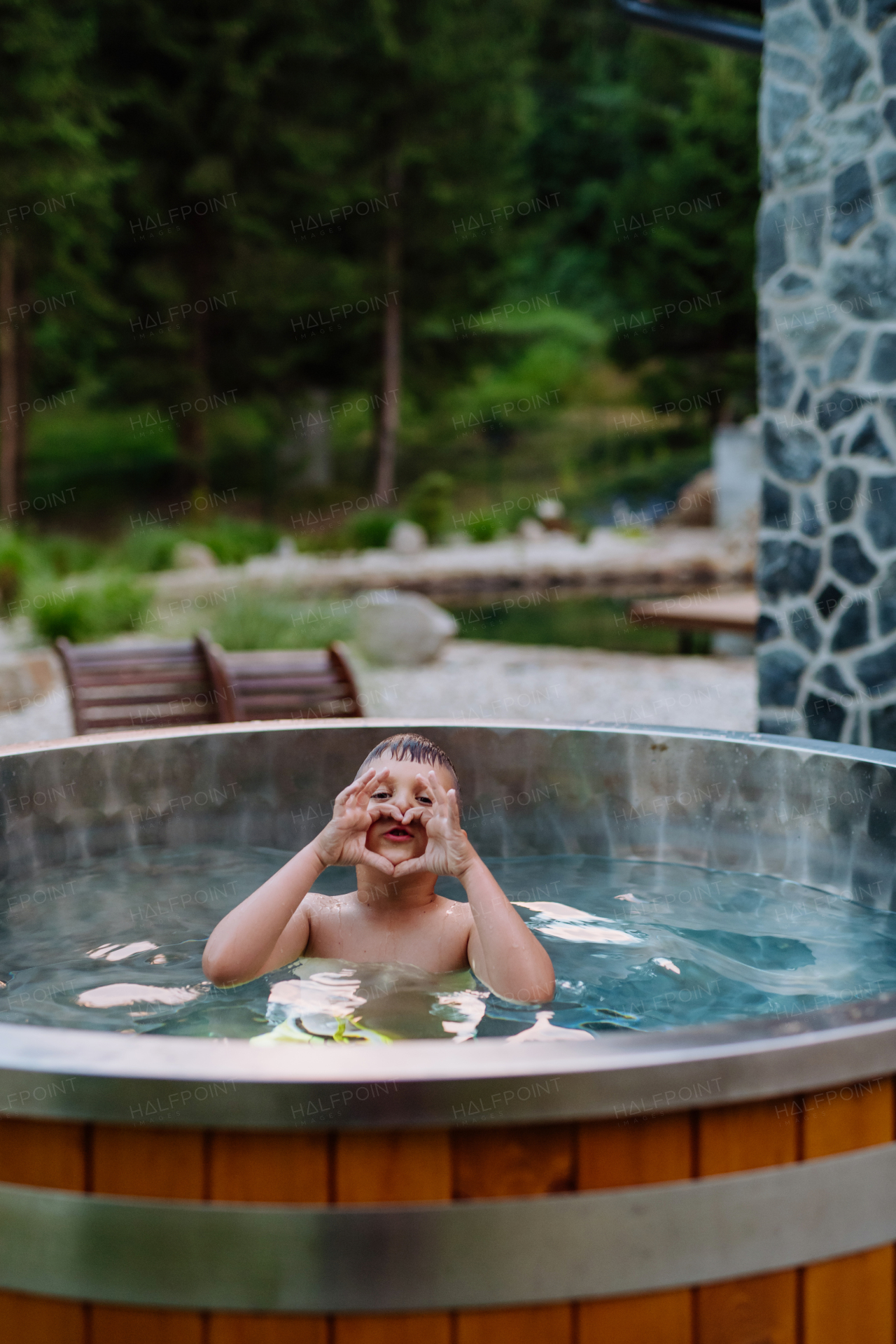 A top view of little boy relaxing in outdoor hot tub. Summer holiday, vacation concept.