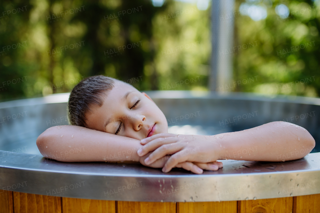 A top view of little boy relaxing with eyes closed in hot tub. Summer holiday, vacation concept.