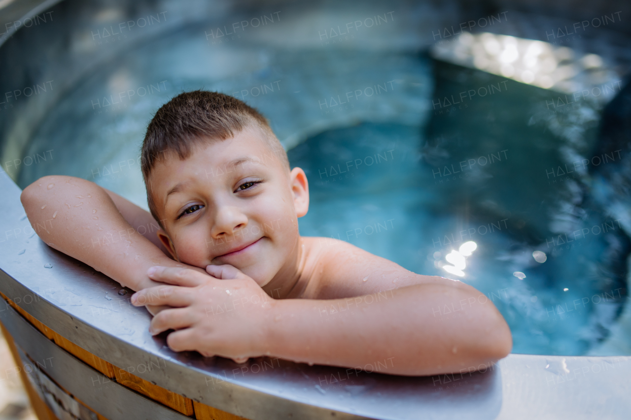 A top view of little boy relaxing in outdoor hot tub. Summer holiday, vacation concept.