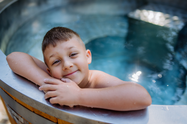 A top view of little boy relaxing in outdoor hot tub. Summer holiday, vacation concept.