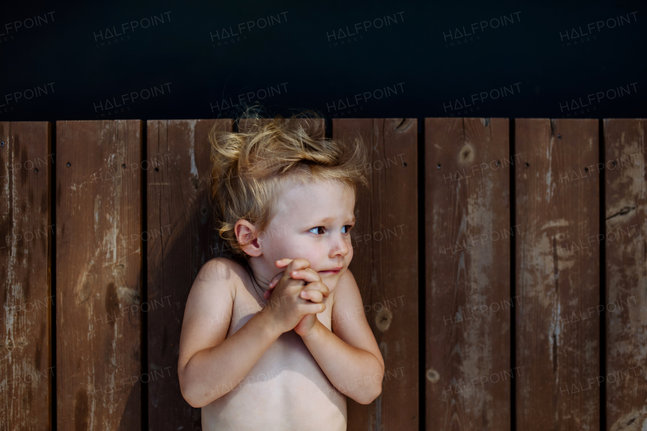 Top view of little girl lying on wooden pier by lake. Summer holiday, vacation concept.