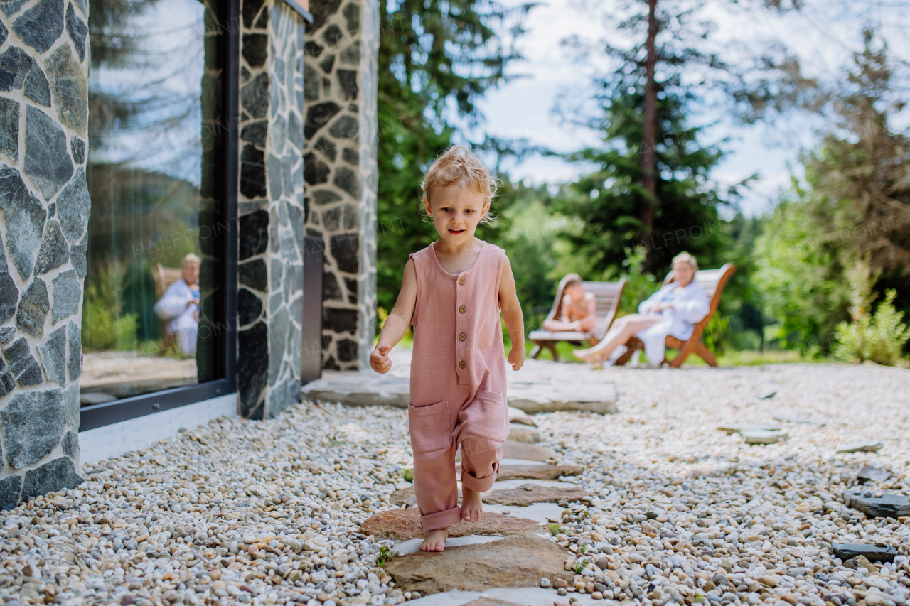 Little girl walking barefoot near a forest cotage,weekend time during summer day.