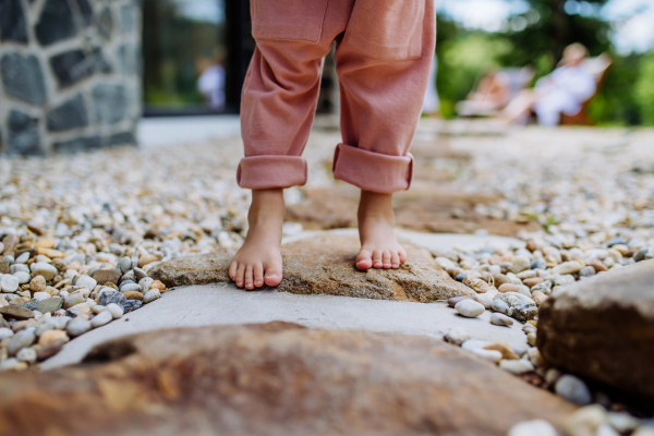 Close-up of little girls barefoot legs, first steps at backyard during a summer day.