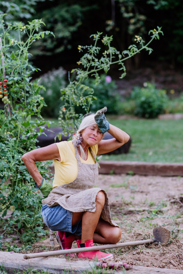 Senior woman resting after working in her garden, having pain in her back.