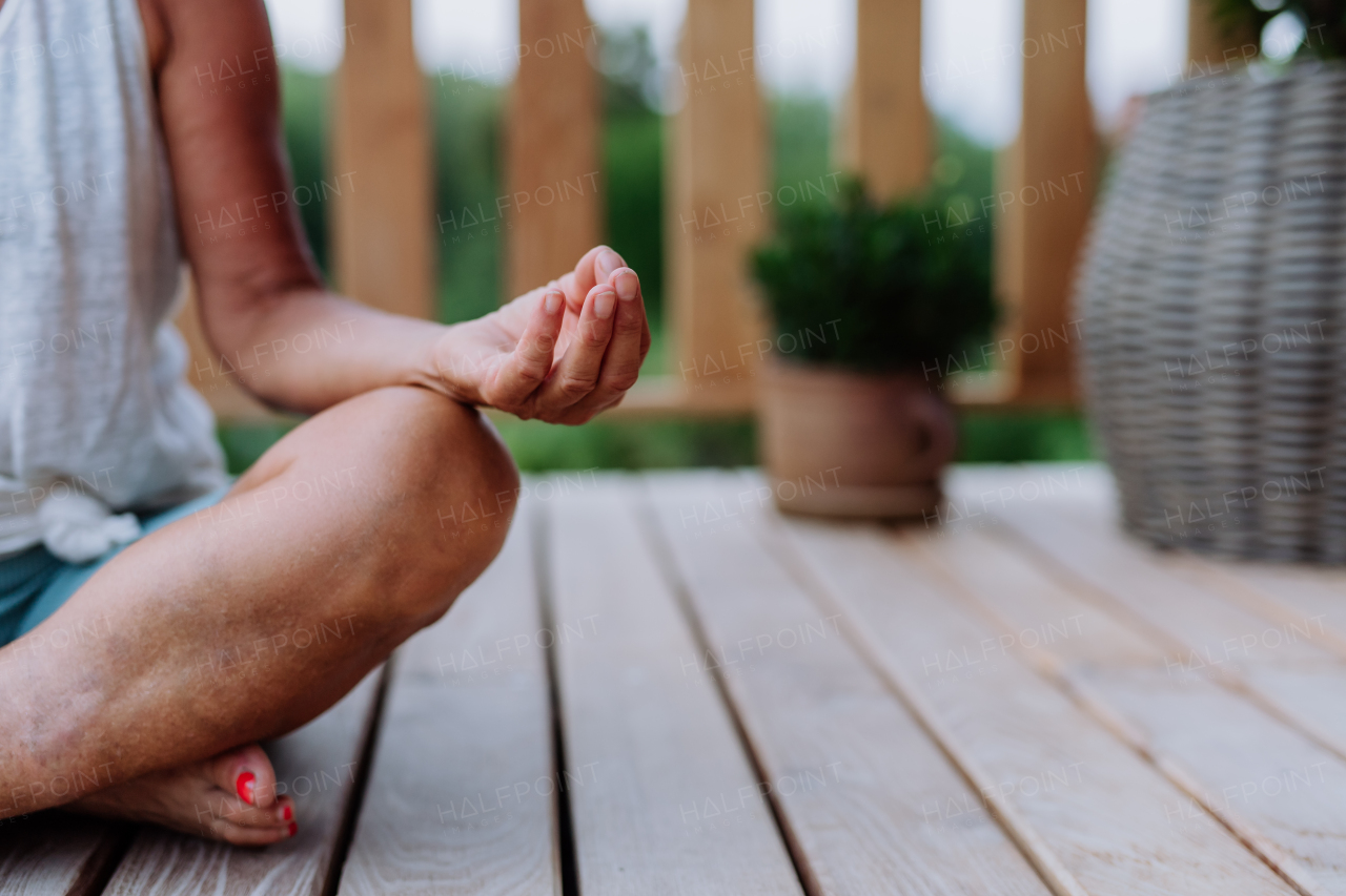 Close-up of a meditation pose by woman sitting at terrace.