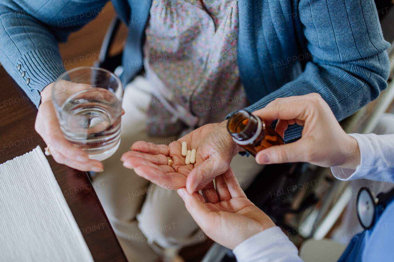 Top view of nurse giving pills to senior woman in her home.