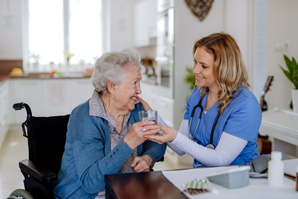 Nurse giving pills to senior woman in her home.