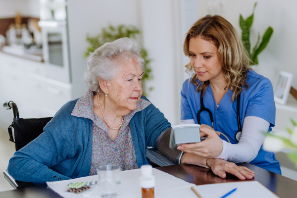 Nurse measuring blood pressuer to senior woman in her home.