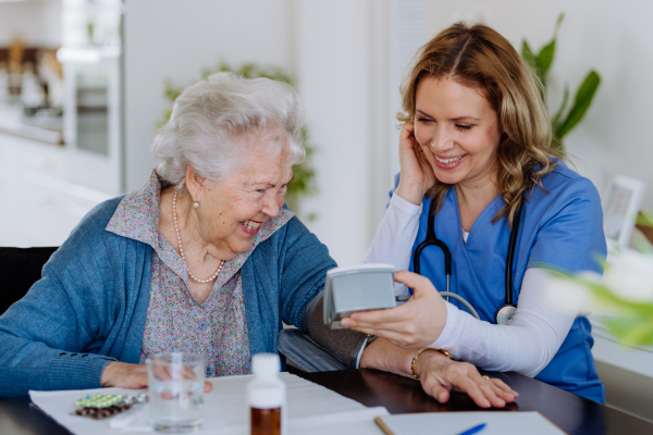 Nurse measuring blood pressuer to senior woman in her home.