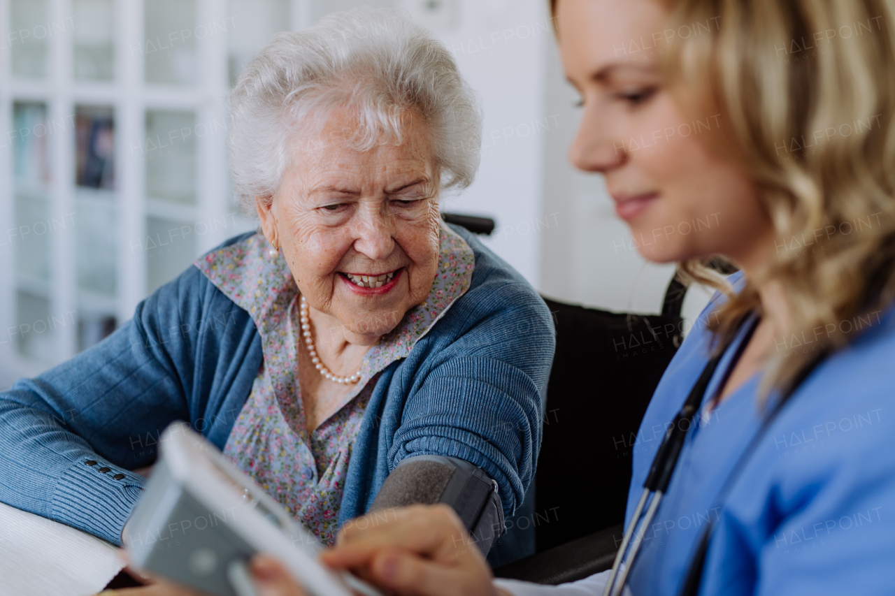 Nurse measuring blood pressuer to senior woman in her home.