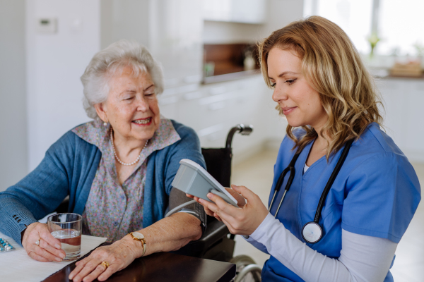 Nurse measuring blood pressuer to senior woman in her home.