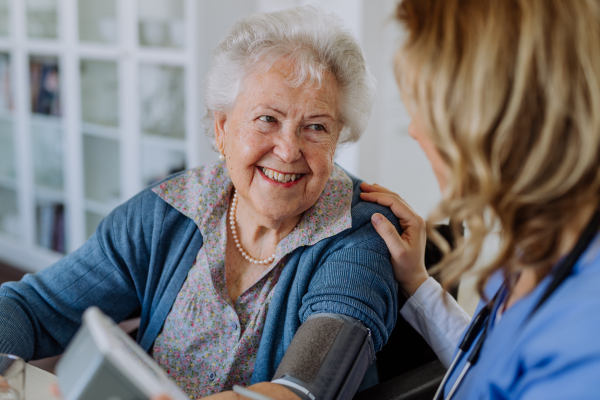 Nurse measuring blood pressuer to senior woman in her home.