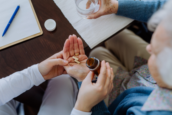 Top view of nurse giving pills to senior woman in her home.