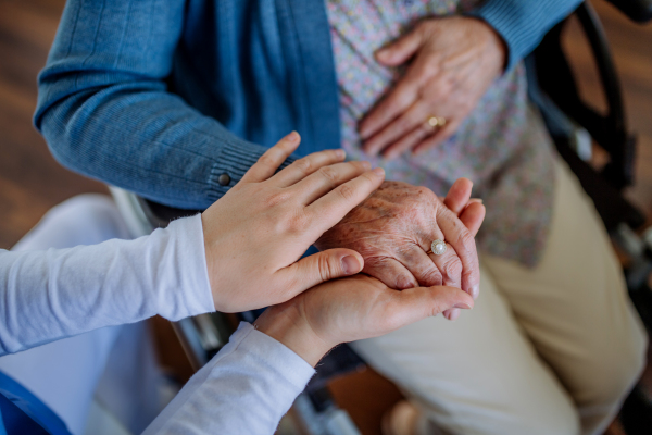 Top view of nurse stroking hands of a senior woman.