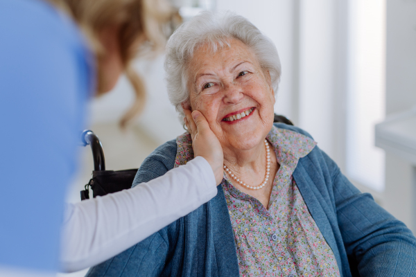 Close up of a nurse stroking cheek of senior woman.