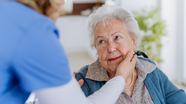 Close up of a nurse stroking cheek of senior woman.