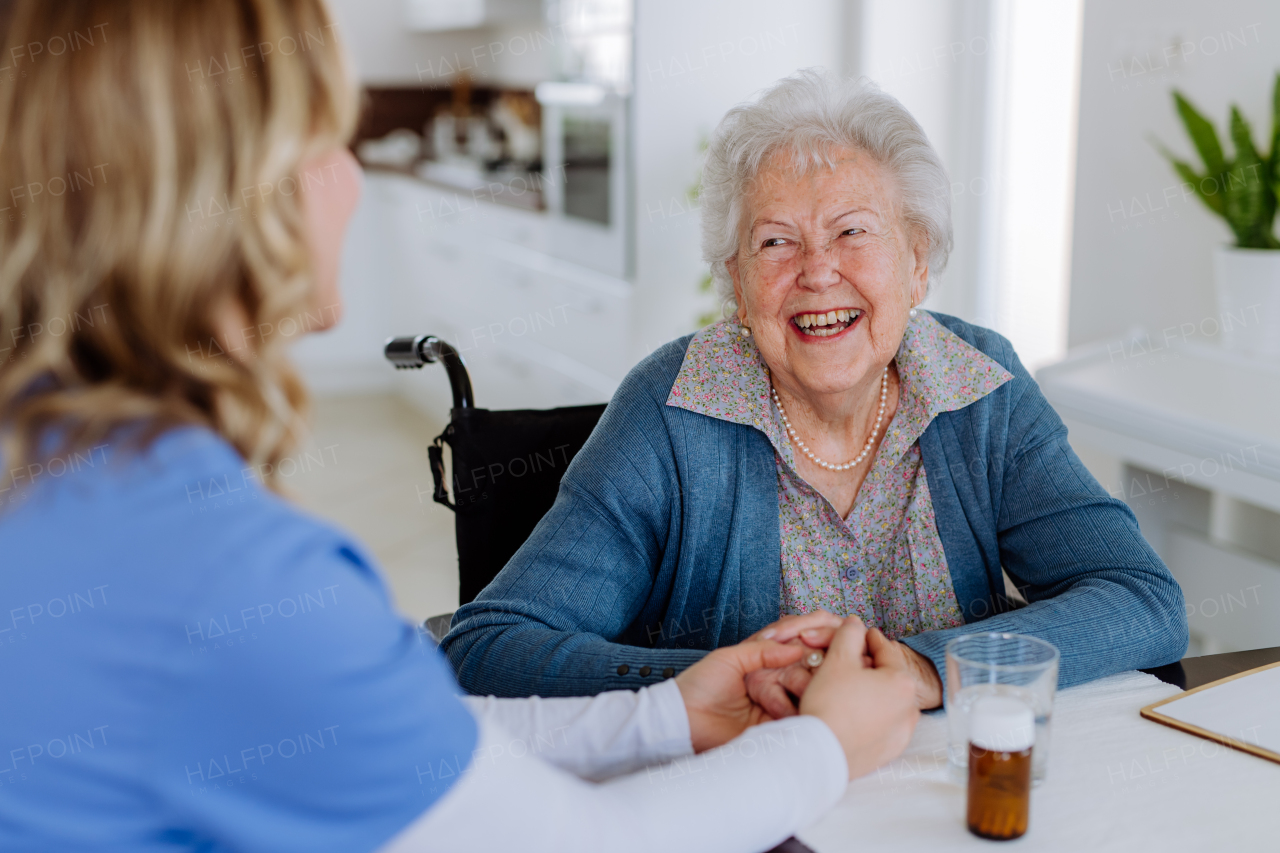 Nurse giving pills to senior woman in her home.