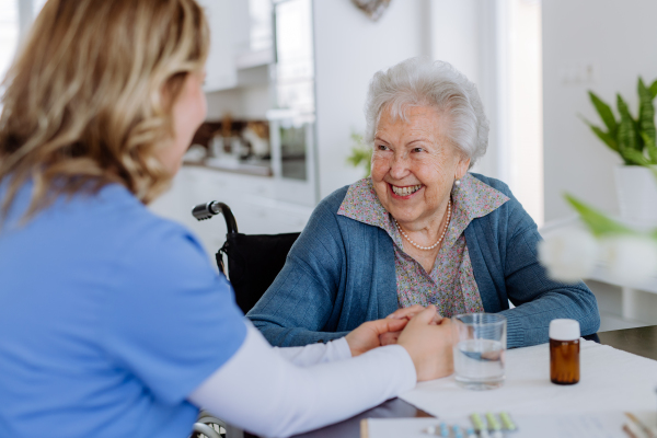 Nurse giving pills to senior woman in her home.