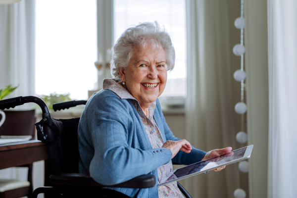 Senior woman on a wheelchair scrolling digital tablet.