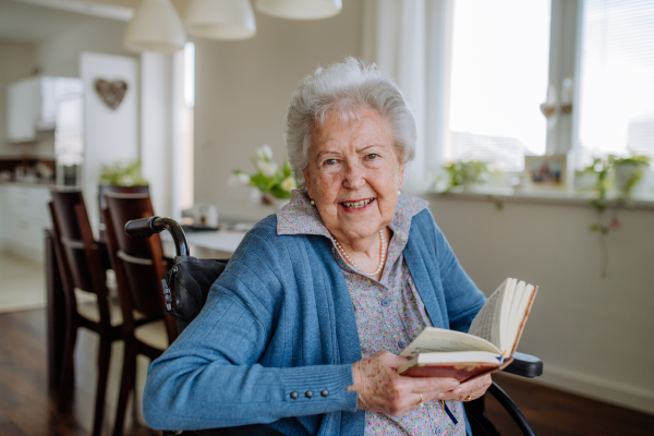 Portrait of senior woman on wheelchair reading book.