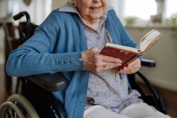 Portrait of senior woman on wheelchair reading book.