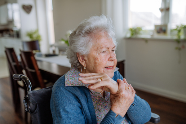 Portrait of senior woman on wheelchair with pain in her arm.