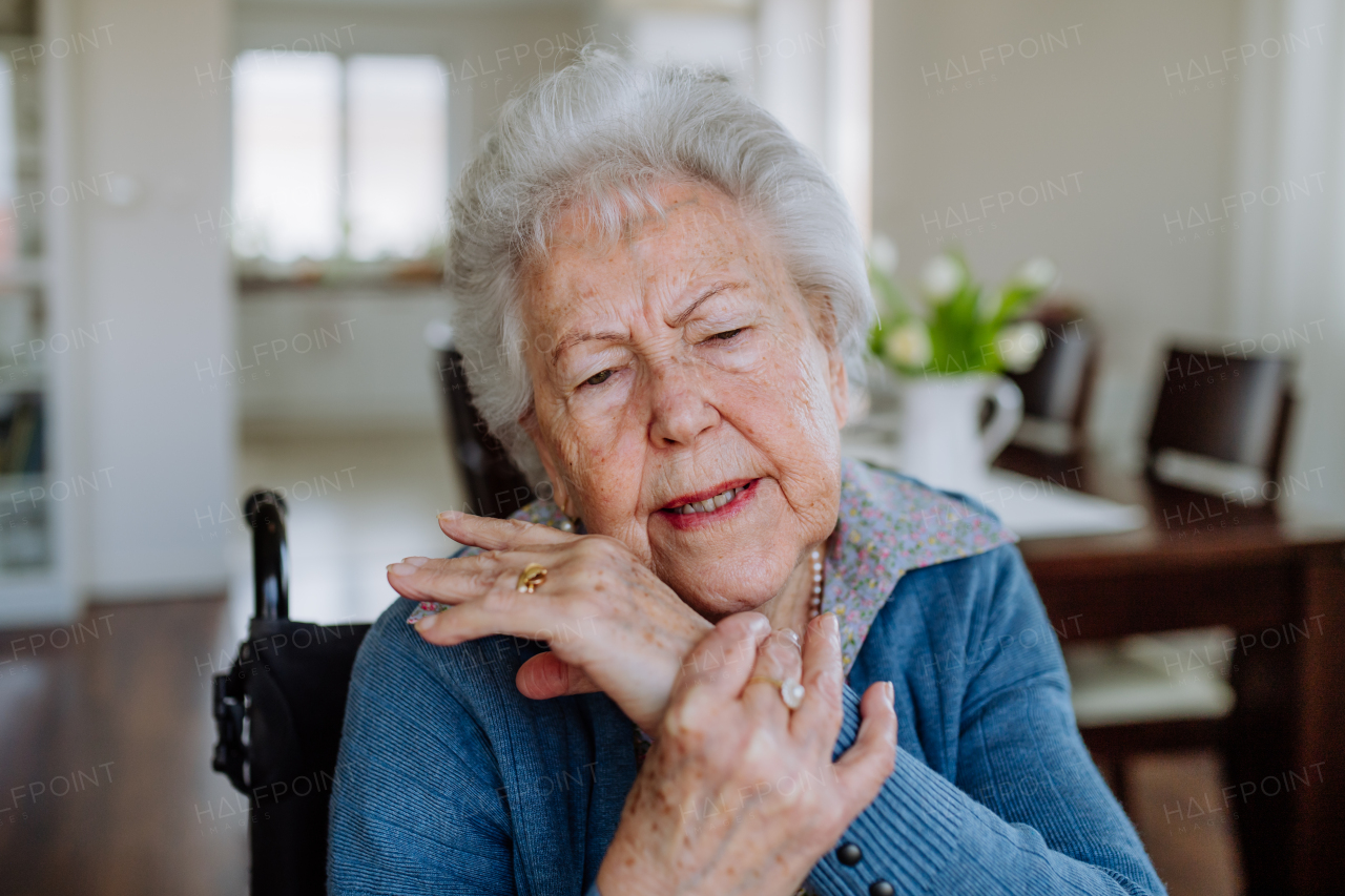 Portrait of senior woman on wheelchair with pain in her arm.