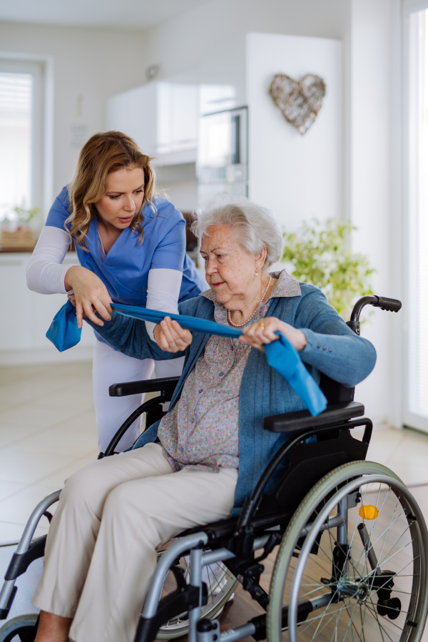 Nurse exercising with senior woman at her home, concept of a healthcare and rehabilitation.