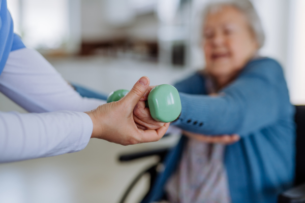 Nurse exercising with senior woman at her home, concept of a healthcare and rehabilitation.