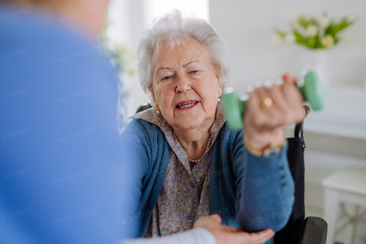 Nurse exercising with senior woman at her home, concept of a healthcare and rehabilitation.