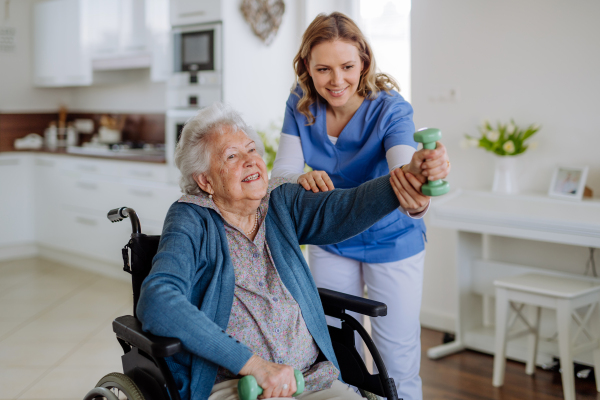 Nurse exercising with senior woman at her home, concept of a healthcare and rehabilitation.