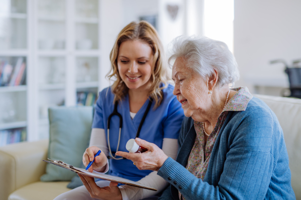 Nurse explaining how to dose medicines to a senior woman.