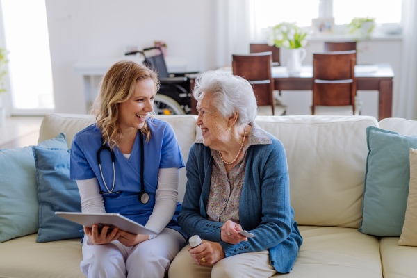 Portrait of caregiver showing something her client in digital tablet.