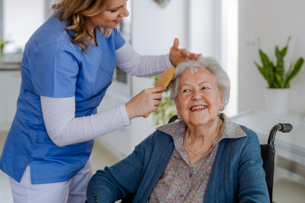 Young nurse doing hairstyle to her senior woman client.